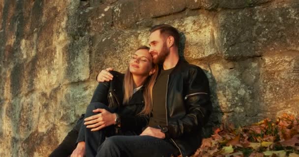 Романтическая пара в любви расслабляется в объятиях у каменной стены, они имеют радость — стоковое видео