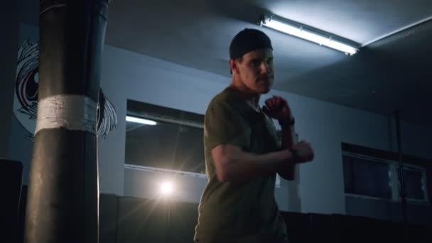 Einsamer Boxer verbessert Boxbewegungen in dunklen Turnhallen in Zeitlupe. Junge Barfußläufer trainieren drinnen auf Sportmatten. Starker Athlet im Fitnessstudio. Sportkonzept. — Stockvideo