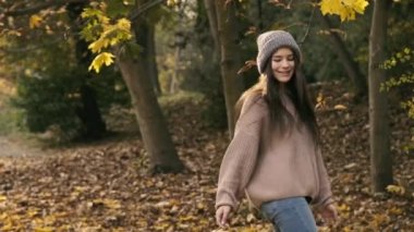 Havalı kız elinde sonbahar yaprağıyla parkta dolanıp duruyor.