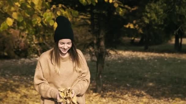 Unbekümmertes junges Mädchen spielt im Park mit Herbstlaub — Stockvideo