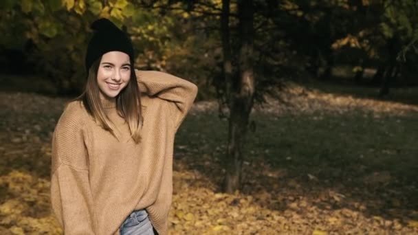 Ευτυχισμένο κορίτσι στέκεται στο πάρκο και χαμογελά από την πτώση φύλλα στο κεφάλι της — Αρχείο Βίντεο