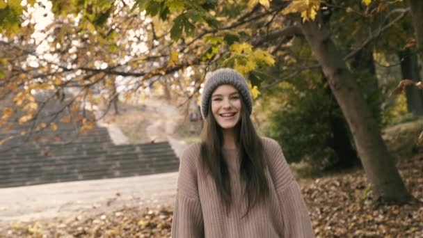 Carefree teen laughs and catches her head at camera in autumn park — Stock Video
