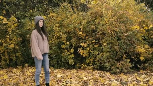 Mutlu kız sonbahar parkında eğleniyor, başlık takıp soyunuyor. — Stok video