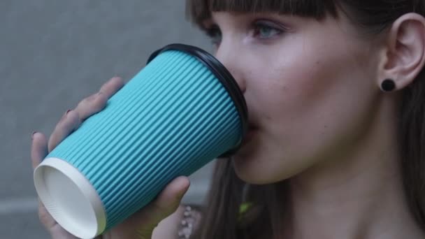 Sluiten portret van mooi meisje drinkt thee en glimlacht op camera op de achtergrond — Stockvideo