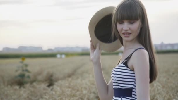 Gelukkig meisje in jurk wervelend met hoed in tarwe veld — Stockvideo
