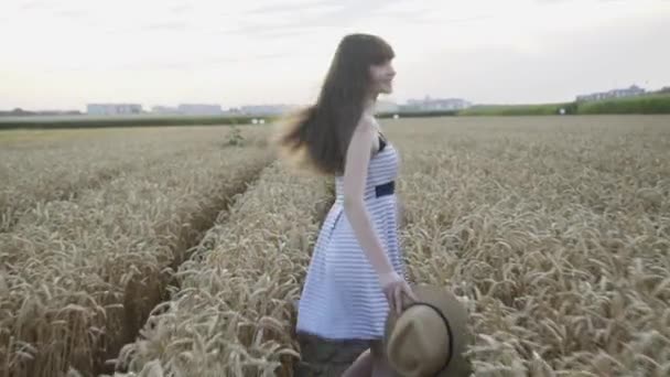 Happy girl with hat running in wheat field, turning and smiling at camera — Stock Video