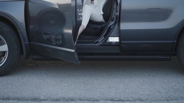 Alacsony a kilátás a magas sarkú cipős nőre, aki kiszáll a kocsiból. — Stock videók