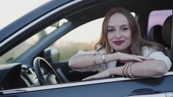 Arabadaki mutlu kadın kameraya döner, kapıya yaslanır ve gülümser. — Stok video