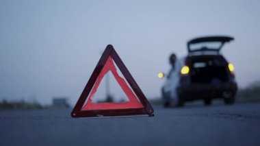 Bulanık arkaplan önündeki yol üzerindeki üçgen işaretinin akşam görünümü