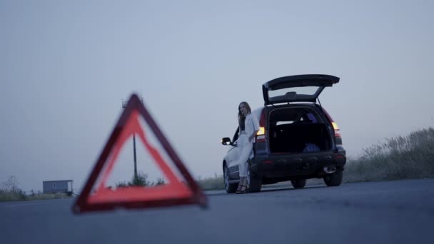 Pemandangan tanda segitiga di jalan di depan seorang wanita yang khawatir dengan siraman di mobil — Stok Video