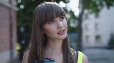 Bir bardak içecekle mutlu bir kız çevreye hayran ve gülümsüyor.