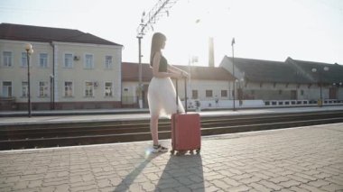 Zarif bir bayan elinde bavuluyla durarak elini uzattı.