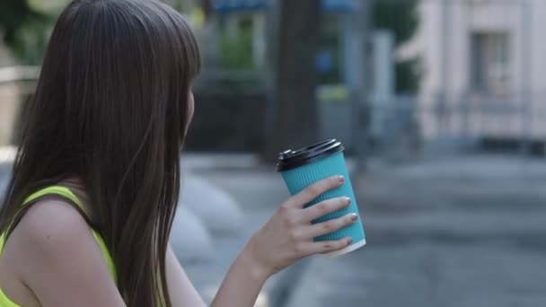 Bemused jong meisje drinkt een kopje thee op straat — Stockvideo