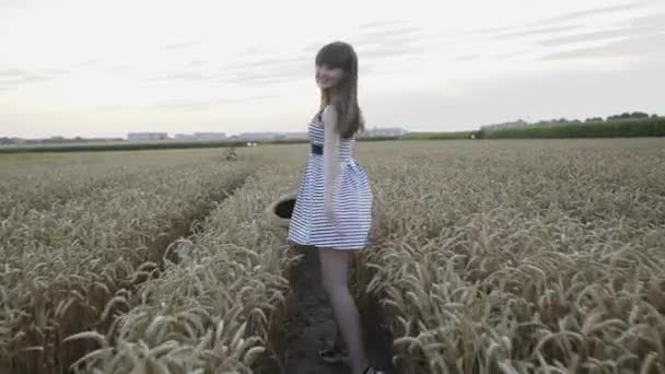 Glückliches Mädchen läuft im Weizenfeld, dreht sich um und lächelt in die Kamera — Stockvideo