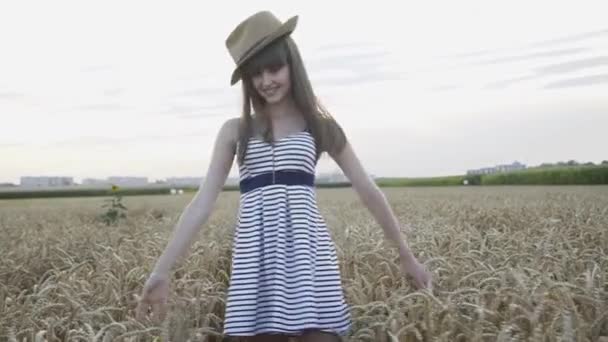 Happy, playful girl poses with hat in wheat field — Stock Video