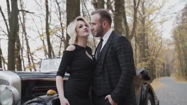 Retrato de la exquisita dama coqueteando y posando en el hombre feliz en el coche en el bosque — Vídeo de stock