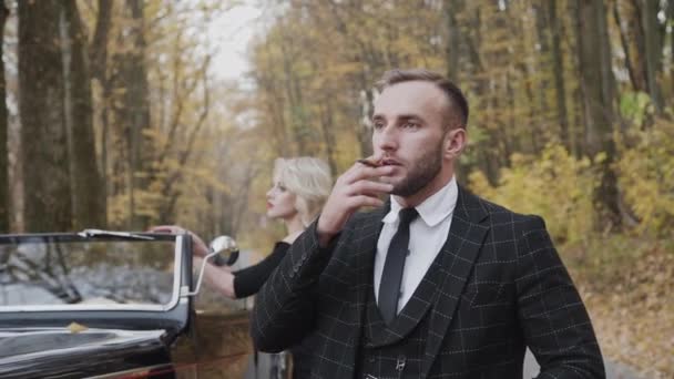 Портрет джентльмена стоит перед его леди и курит сигару в лесу — стоковое видео
