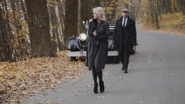 Bello signore in capispalla viene alla sua bionda sorridente nel parco autunnale — Video Stock