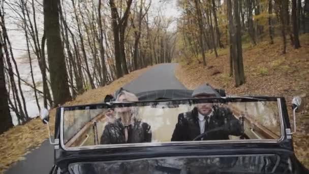 Романтична пара катається в ретро кабріолеті в осінньому лісі і посміхається — стокове відео
