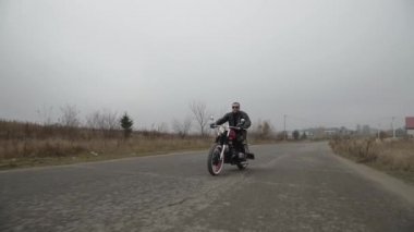 Buğday tarlasının yakınındaki yolda giden acımasız motosikletçi.
