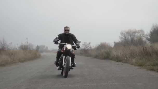 Retrato del motociclista en la carretera conduciendo con los esquivos en la cámara — Vídeos de Stock