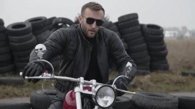 Motosiklette kameraya bakan vahşi bir adamın portresi.