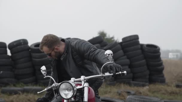 Portræt af motorcyklist på motorcykel kigger på kamera nær dæk – Stock-video