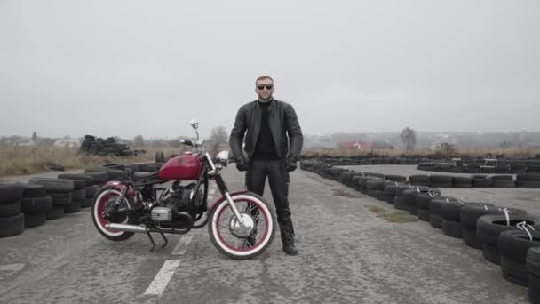 Portret brutalnego motocyklisty w okularach przeciętych przez dłonie i patrzącego w oddali — Wideo stockowe