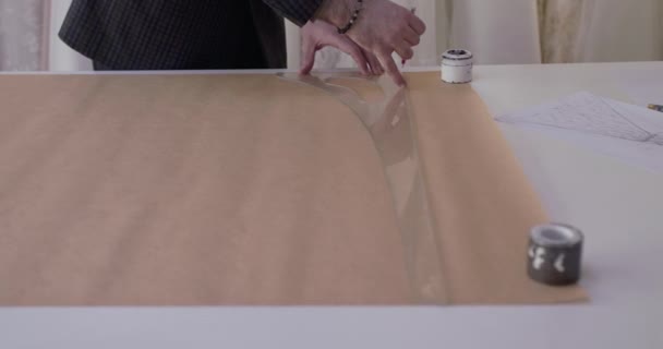 Tailors hands drawing a curve on tissue with sleeve curves ruler on desktop — Stock Video