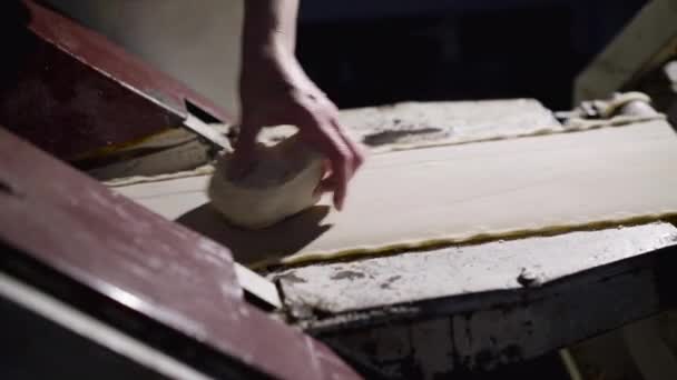 Bakkers hand neemt de vorm van rauw deeg voor het bakken van brood in de productie-apparatuur — Stockvideo