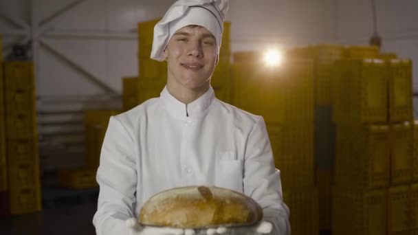 Пекар в уніформі подарує на камеру свіжоспечений хліб — стокове відео