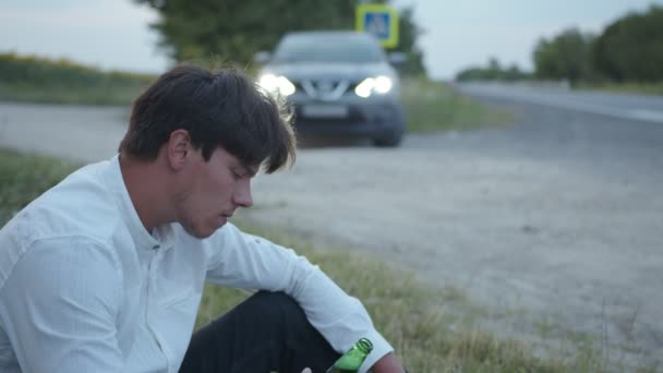 Людина сидить на траві і чекає на допомогу — стокове відео