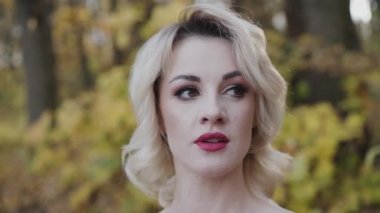 Makyajlı güzel bir bayanın yakın portresi yana bakar ve gülümser.