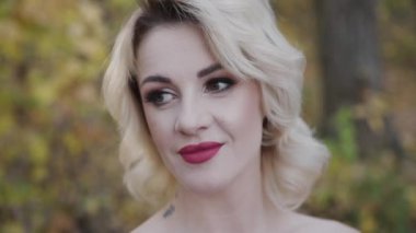 Güz parkında gülümseyen güzel bir kadının yakın portresi.