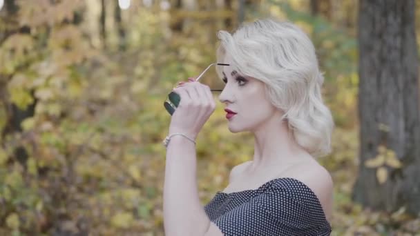 Ritratto di bionda seducente con labbra rosse si mette gli occhiali da sole — Video Stock