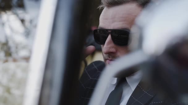 Fechar vista de homem bonito em óculos de sol sentado em carro retro — Vídeo de Stock