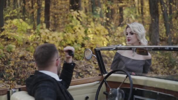 ロマンチックなカップルの肖像画は、レトロな車でお互いを見て — ストック動画