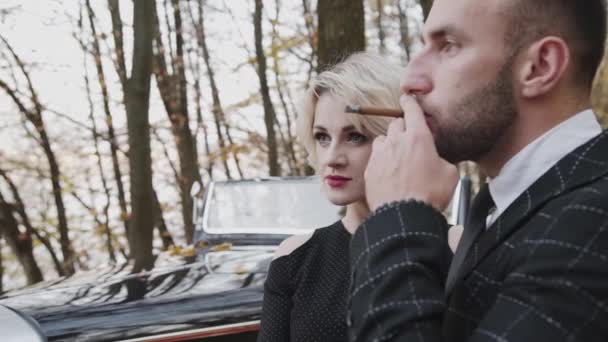 Couple glamour, homme fumant cigare et ils regardent droit au cabriolet rétro — Video