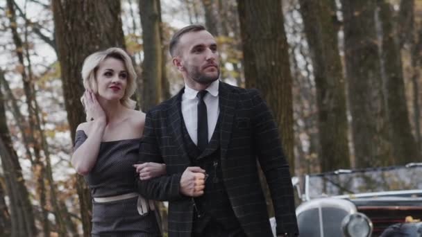 Plimbare mândră de cuplu romantic care se uită deoparte cu zâmbetul în parcul de toamnă — Videoclip de stoc