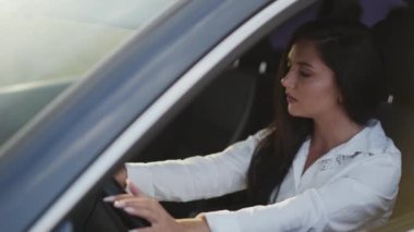 Arabadaki endişeli kadın gidonu parmaklarıyla vuruyor ve havayı dağıtıyor.