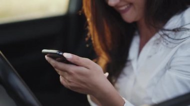 Arabada akıllı telefon kullanırken gülümseyen mutlu kızın yakın görüntüsü