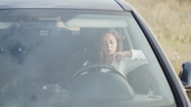 Arabada akıllı telefon kullanırken gülümseyen kızın ön camından bak.