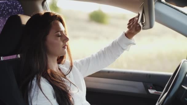 Gadis berambut panjang mengoleskan lipstik di cermin depan mobil. — Stok Video