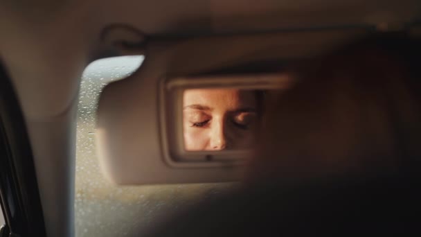 Отражение женщины в переднем зеркале автомобиля, которая открывает глаза — стоковое видео