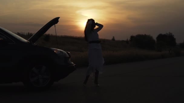 Вид уставшей женщины нервничает перед разбитым автомобилем глубоким вечером за городом — стоковое видео