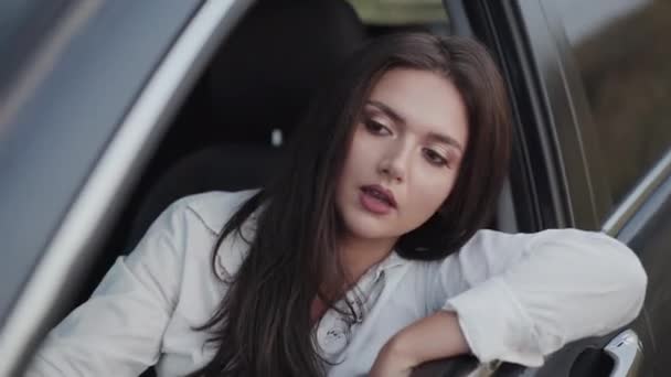 Woman in car looks out, talks with gestures and smiles — Stock Video