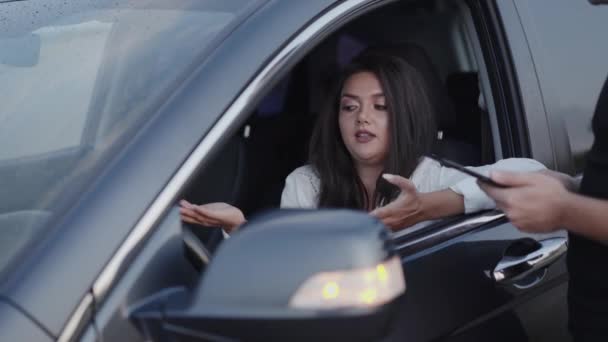 Señora en el coche habla con el oficial de servicio, mira gadget y se alegra — Vídeo de stock