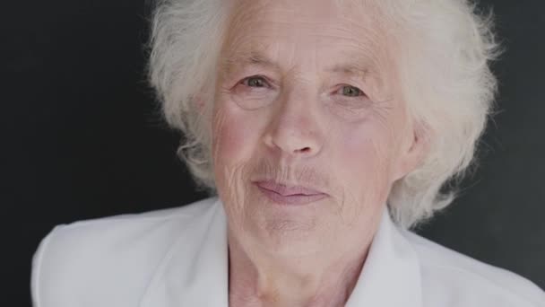 Retrato de cabelos grisalhos avó fala e sorri para a câmera no fundo — Vídeo de Stock