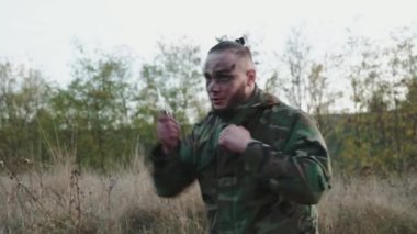 Kamuflaj üniformalı bir avcı uçağı dışarıda kameraya çarpıyor. Yavaşça.