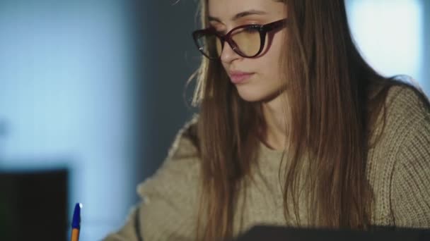 Trött student anteckningar vid skrivbordet, tar av glasögon och tänker när luta sig mot handen — Stockvideo